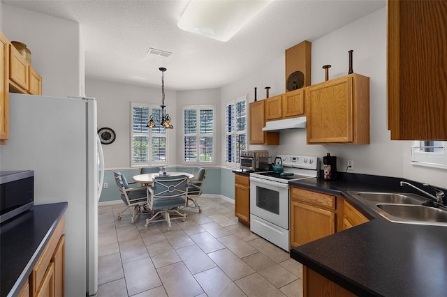 532 Casanova Ct, Kissimmee, FL 34759 - kitchen with white appliances, under cabinet range hood, a sink, dark countertops, and hanging light fixtures