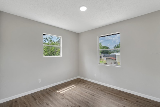 1840 Lillian Dr, Saint Cloud, FL 34771 - empty room featuring baseboards, healthy amount of natural light, wood finished floors, and a textured ceiling