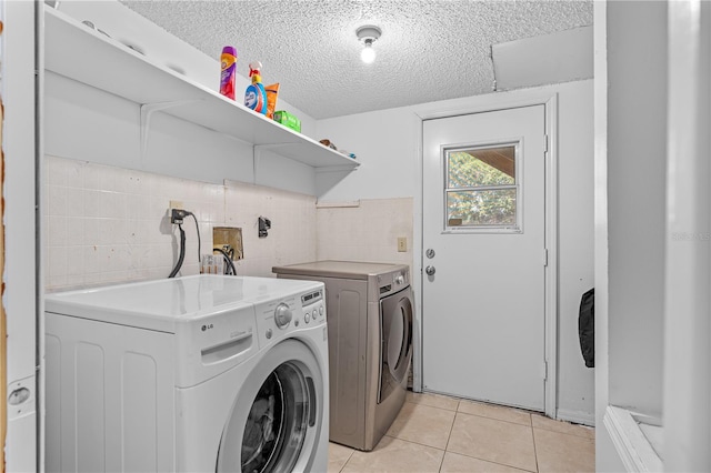 2500 Derby Dr, Kissimmee, FL 34744 - laundry area with washing machine and dryer, a textured ceiling, light tile patterned flooring, and tile walls