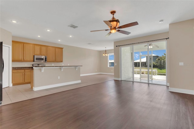 kitchen with stainless steel microwave, open floor plan, ceiling fan, light brown cabinetry, and recessed lighting