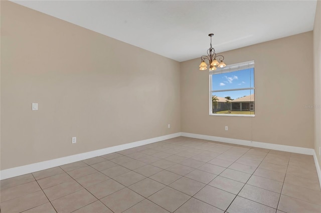 empty room featuring a chandelier, light tile patterned floors, and baseboards