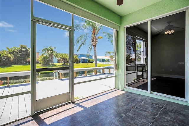 unfurnished sunroom with ceiling fan and a water view
