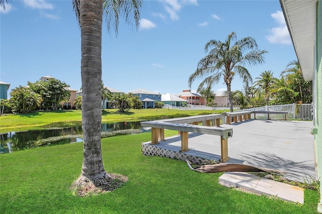 view of green lawn featuring a residential view and a deck with water view