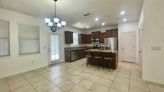 4450 Capital Blvd, Saint Cloud, FL 34769 - kitchen with stainless steel appliances, light tile patterned floors, dark brown cabinets, a breakfast bar area, and recessed lighting
