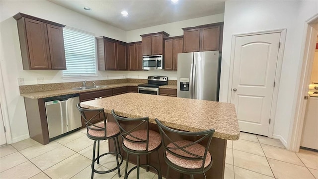 4450 Capital Blvd, Saint Cloud, FL 34769 - kitchen featuring appliances with stainless steel finishes, dark brown cabinets, light tile patterned flooring, a sink, and a center island