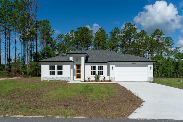 prairie-style home featuring a garage, stone siding, stucco siding, concrete driveway, and a front yard