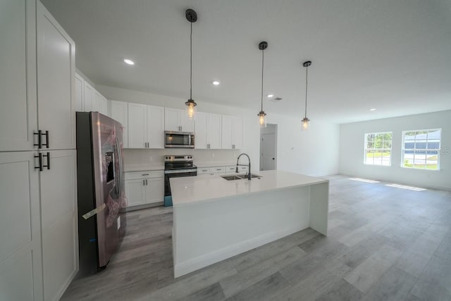 kitchen with appliances with stainless steel finishes, a sink, light wood-type flooring, white cabinetry, and light countertops