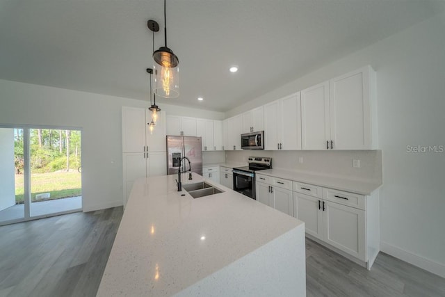 kitchen featuring appliances with stainless steel finishes, a sink, light wood-type flooring, white cabinetry, and recessed lighting