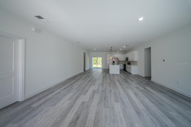 unfurnished living room with light wood-style floors, recessed lighting, and baseboards