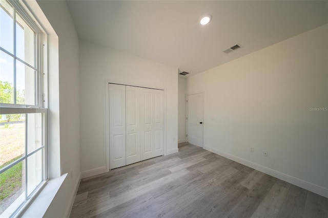 unfurnished bedroom featuring light wood finished floors, multiple windows, baseboards, and recessed lighting