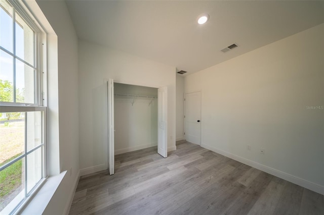 unfurnished bedroom with light wood finished floors, multiple windows, baseboards, and recessed lighting