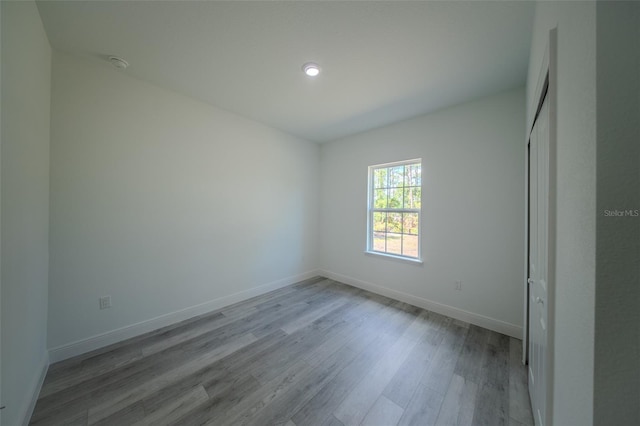 empty room with wood finished floors, baseboards, and recessed lighting