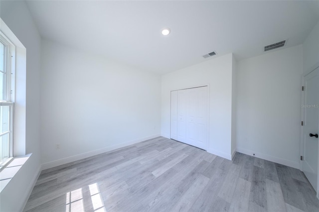 unfurnished bedroom featuring light wood-style flooring, baseboards, a closet, and recessed lighting