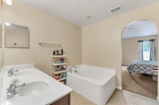 510 Lobelia Dr, Davenport, FL 33837 - ensuite bathroom featuring tile patterned floors, a garden tub, a textured ceiling, and double vanity