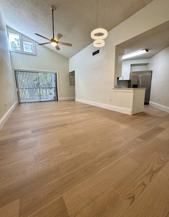 3621 Atrium Dr Unit U-4, Orlando, FL 32822 - unfurnished living room featuring ceiling fan, a textured ceiling, high vaulted ceiling, light wood finished floors, and baseboards