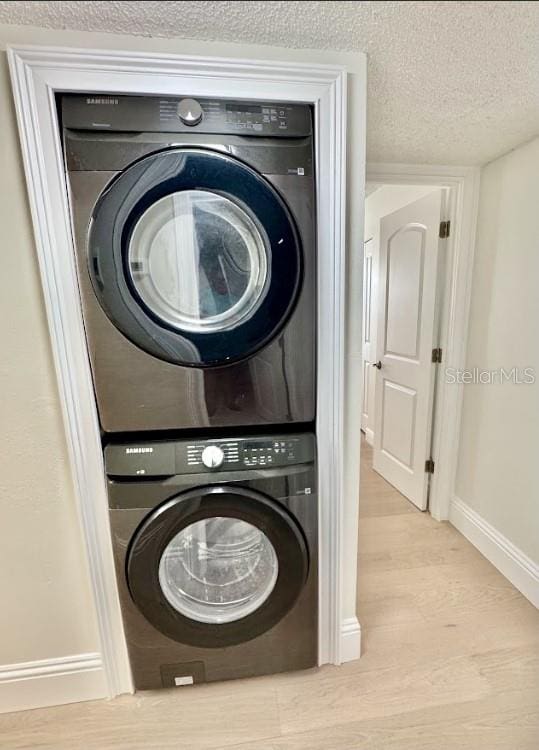 3621 Atrium Dr Unit U-4, Orlando, FL 32822 - washroom featuring stacked washing machine and dryer, wood finished floors, baseboards, and a textured ceiling