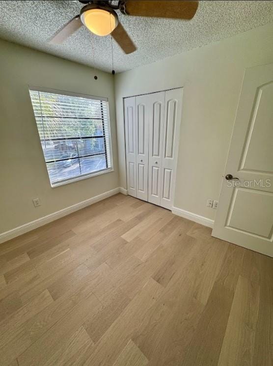 3621 Atrium Dr Unit U-4, Orlando, FL 32822 - unfurnished bedroom featuring light wood-style floors, a closet, a textured ceiling, baseboards, and a ceiling fan