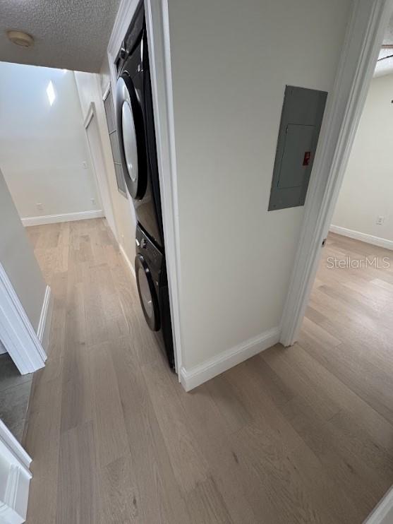3621 Atrium Dr Unit U-4, Orlando, FL 32822 - laundry area with electric panel, estacked washer and dryer, light wood-style flooring, baseboards, and a textured ceiling