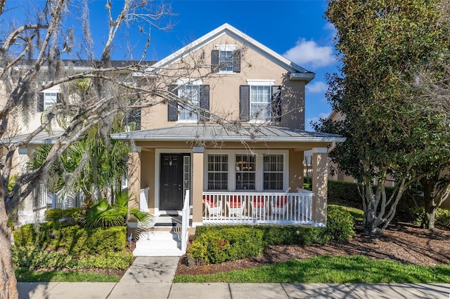 9141 Camden Gardens St, Orlando, FL 32827 - traditional home with stucco siding, covered porch, a standing seam roof, and metal roof