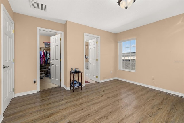 9141 Camden Gardens St, Orlando, FL 32827 - unfurnished bedroom with wood finished floors, baseboards, a walk in closet, a closet, and connected bathroom