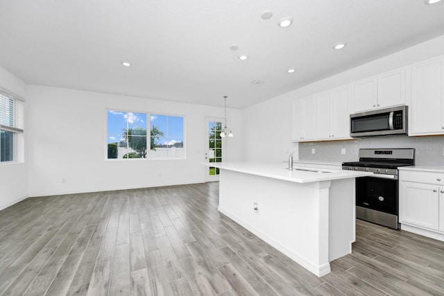 809 Benoi Dr, Davenport, FL 33896 - kitchen featuring appliances with stainless steel finishes, light wood finished floors, light countertops, a sink, and white cabinetry