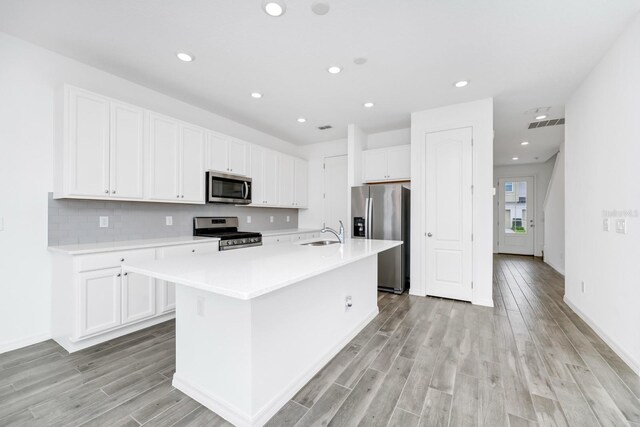 809 Benoi Dr, Davenport, FL 33896 - kitchen featuring stainless steel appliances, a sink, a center island with sink, light countertops, and light wood-style floors