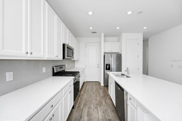 809 Benoi Dr, Davenport, FL 33896 - kitchen with stainless steel appliances, a sink, wood finished floors, white cabinetry, and light countertops