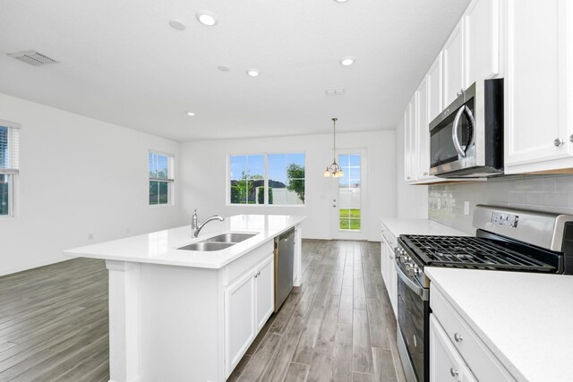809 Benoi Dr, Davenport, FL 33896 - kitchen with appliances with stainless steel finishes, a sink, light wood-type flooring, white cabinets, and light countertops