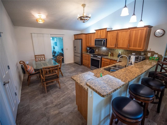2167 Kerwood Loop, The Villages, FL 32162 - kitchen featuring appliances with stainless steel finishes, a sink, brown cabinets, a peninsula, and light stone counters