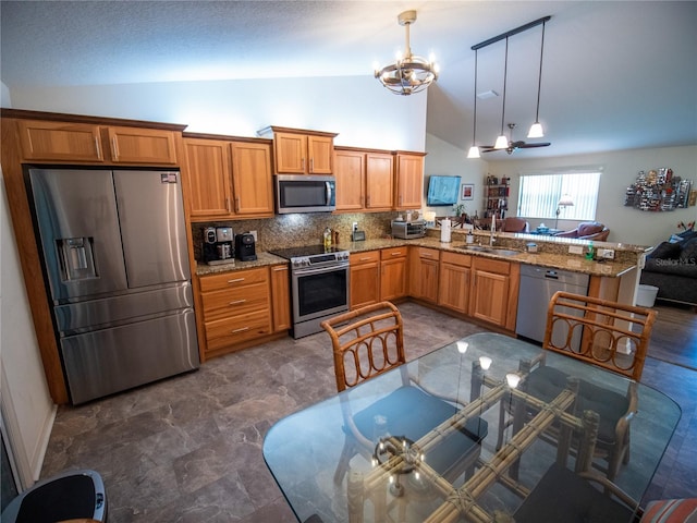 2167 Kerwood Loop, The Villages, FL 32162 - kitchen featuring stainless steel appliances, a sink, a chandelier, brown cabinetry, and light stone counters