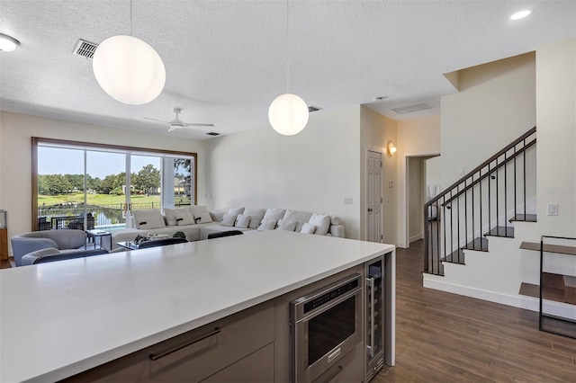 8430 Woburn Ct, Windermere, FL 34786 - kitchen with stainless steel microwave, a textured ceiling, open floor plan, dark wood-style flooring, and light countertops