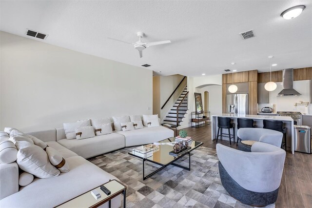 8430 Woburn Ct, Windermere, FL 34786 - living area with arched walkways, a ceiling fan, stairway, dark wood-type flooring, and a textured ceiling