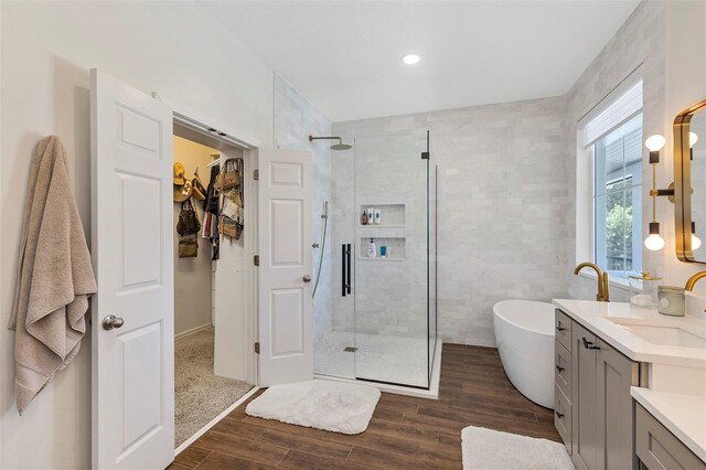 8430 Woburn Ct, Windermere, FL 34786 - bathroom with vanity, a shower stall, a freestanding tub, wood finished floors, and tile walls