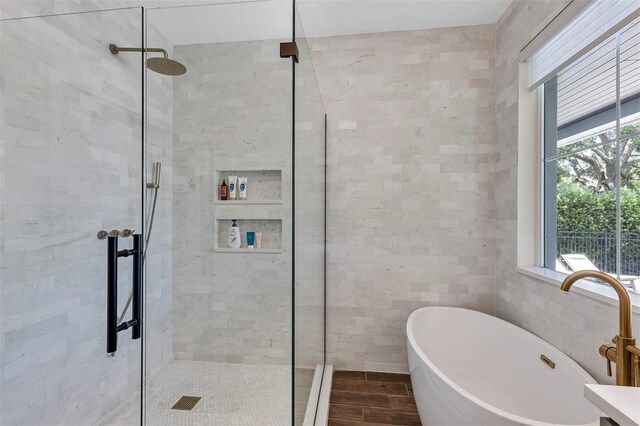 8430 Woburn Ct, Windermere, FL 34786 - bathroom featuring a shower stall, a freestanding tub, tile walls, and wood finished floors