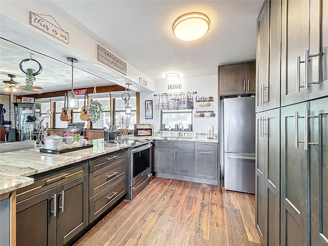 3788 N Econlockhatchee Trl, Orlando, FL 32817 - kitchen with stainless steel appliances, a peninsula, a sink, light stone countertops, and light wood-type flooring