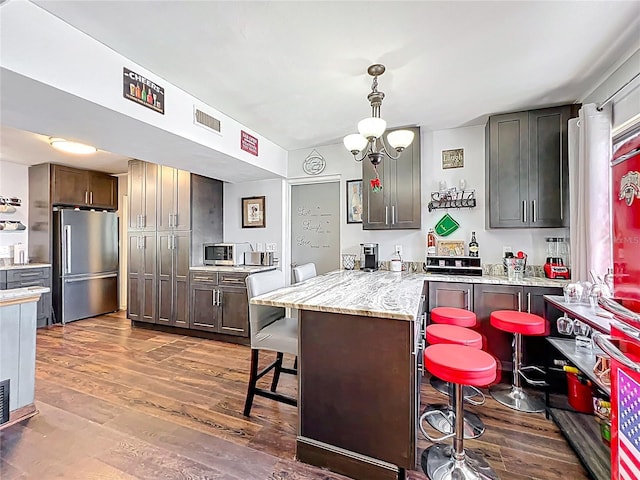 3788 N Econlockhatchee Trl, Orlando, FL 32817 - kitchen with freestanding refrigerator, a breakfast bar area, a peninsula, and dark wood finished floors