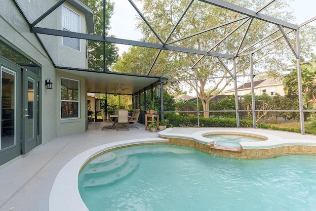 view of pool featuring a patio, ceiling fan, glass enclosure, and a pool with connected hot tub