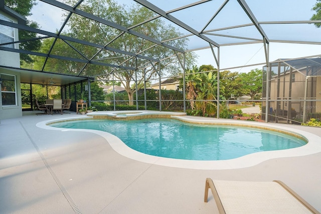 view of swimming pool featuring a patio, a pool with connected hot tub, and glass enclosure