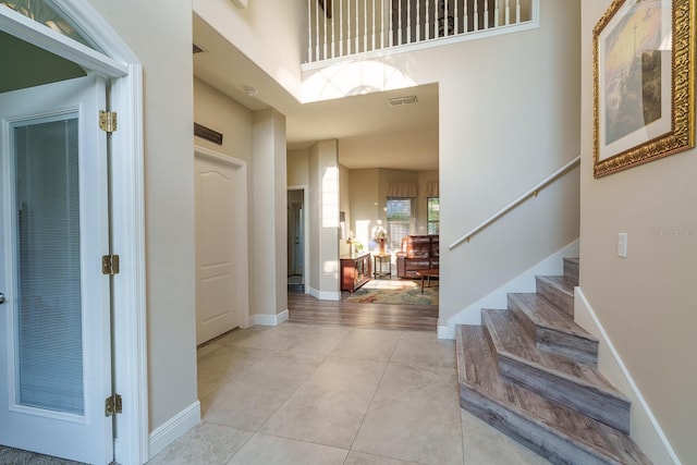 foyer featuring stairs, light tile patterned floors, and baseboards