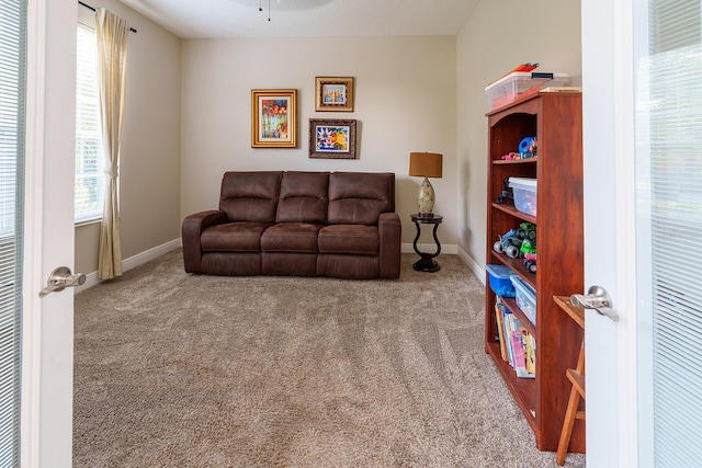carpeted living area with baseboards and ceiling fan