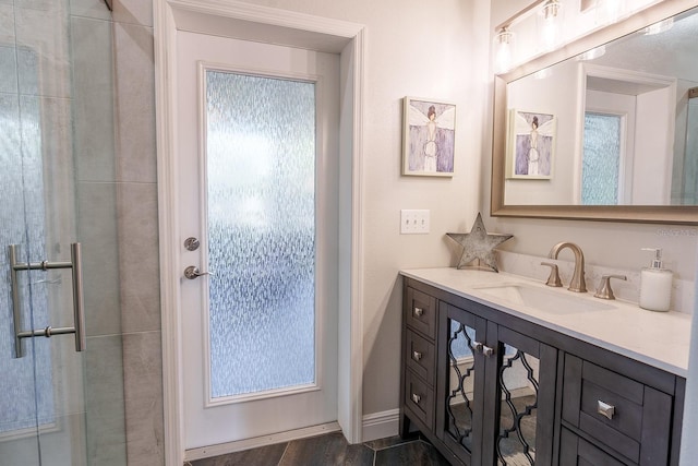 bathroom with an enclosed shower, vanity, and wood finished floors