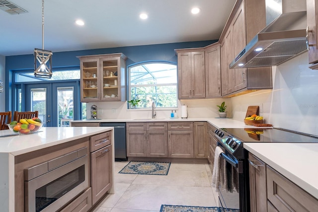 kitchen featuring stainless steel appliances, wall chimney range hood, recessed lighting, a sink, and light countertops