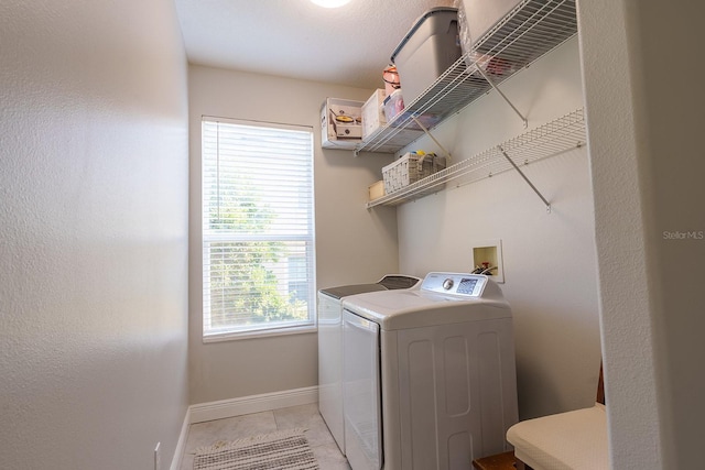 clothes washing area featuring washing machine and dryer, baseboards, and light tile patterned floors