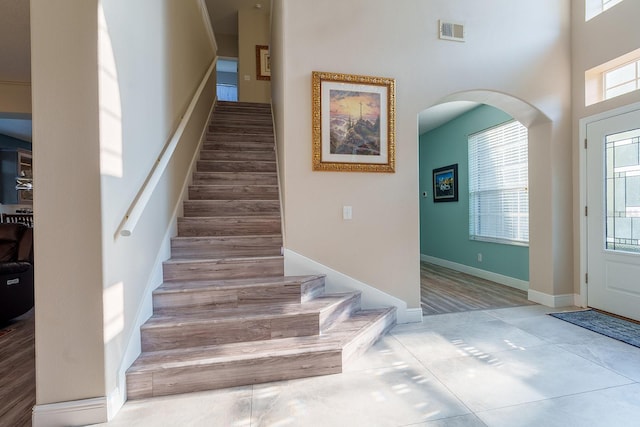 entrance foyer featuring stairway, arched walkways, and tile patterned flooring