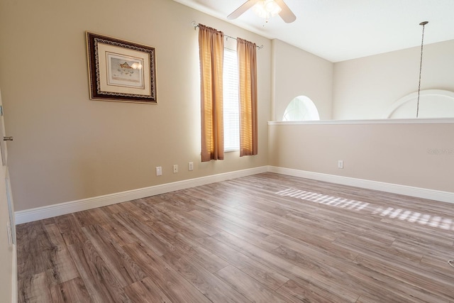 spare room with a ceiling fan, wood finished floors, and baseboards