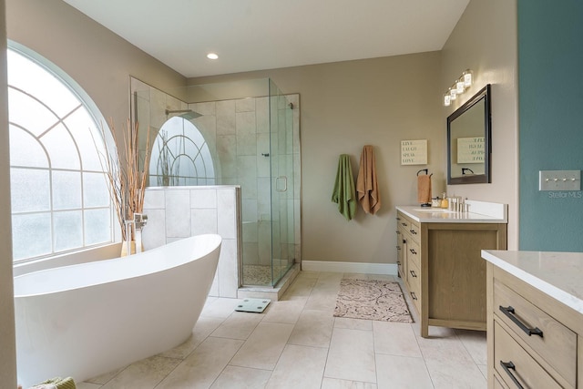 bathroom with vanity, a shower stall, a soaking tub, tile patterned floors, and baseboards