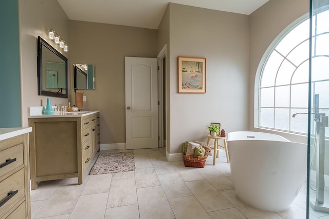 bathroom with a soaking tub, vanity, and baseboards