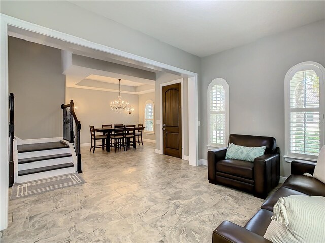 8491 Pippen Dr, Orlando, FL 32836 - living room with a chandelier, baseboards, a raised ceiling, arched walkways, and stairway