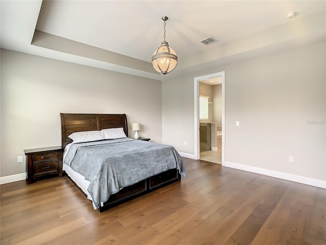 8491 Pippen Dr, Orlando, FL 32836 - bedroom featuring baseboards, wood finished floors, ensuite bath, and a tray ceiling