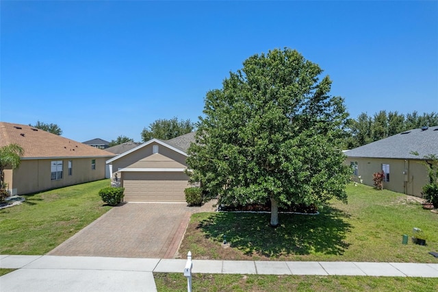 view of front of home with decorative driveway, a front yard, and an attached garage